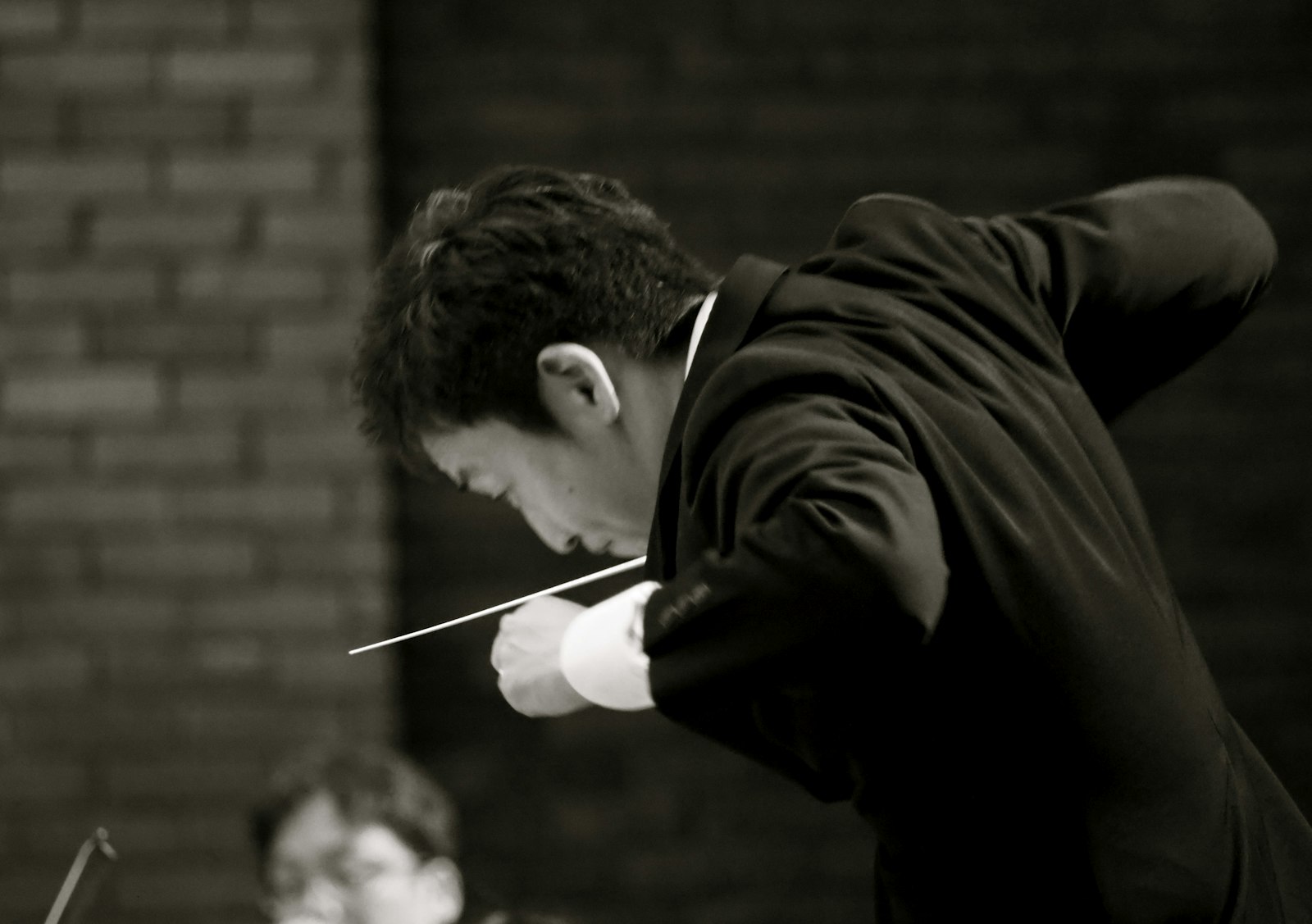 Conductor with baton raised during a live orchestral performance — the BANI leadership metaphor in action